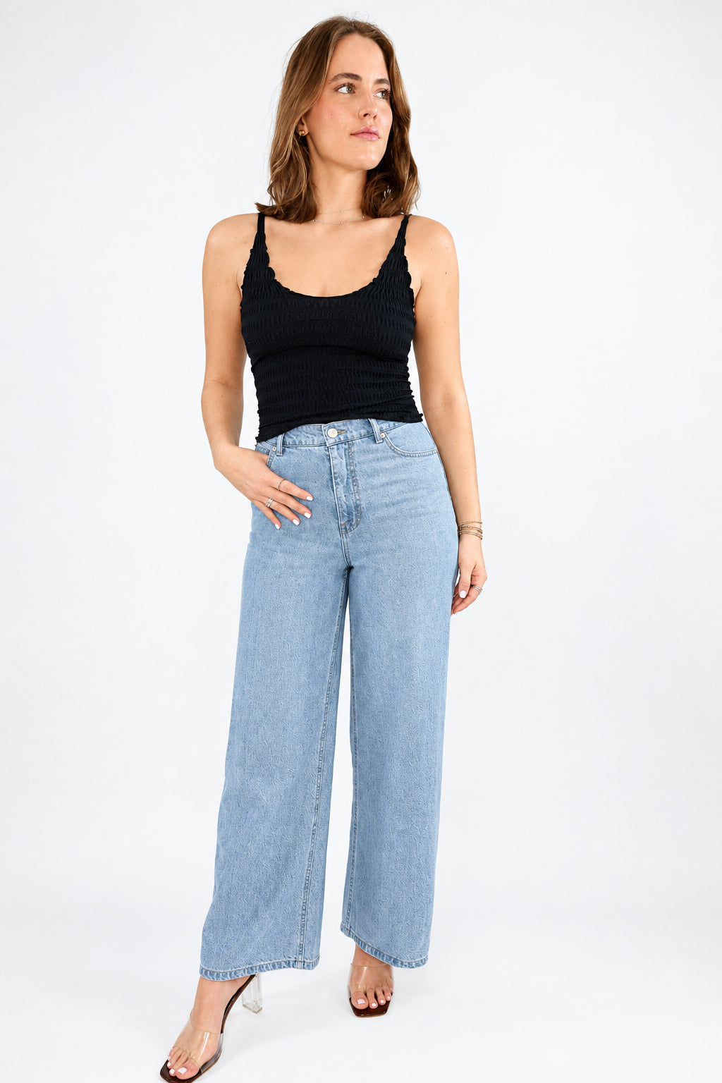 A person wearing Z Supply light-wash wide-leg denim jeans with a black top and white sneakers, standing against a plain white studio background.