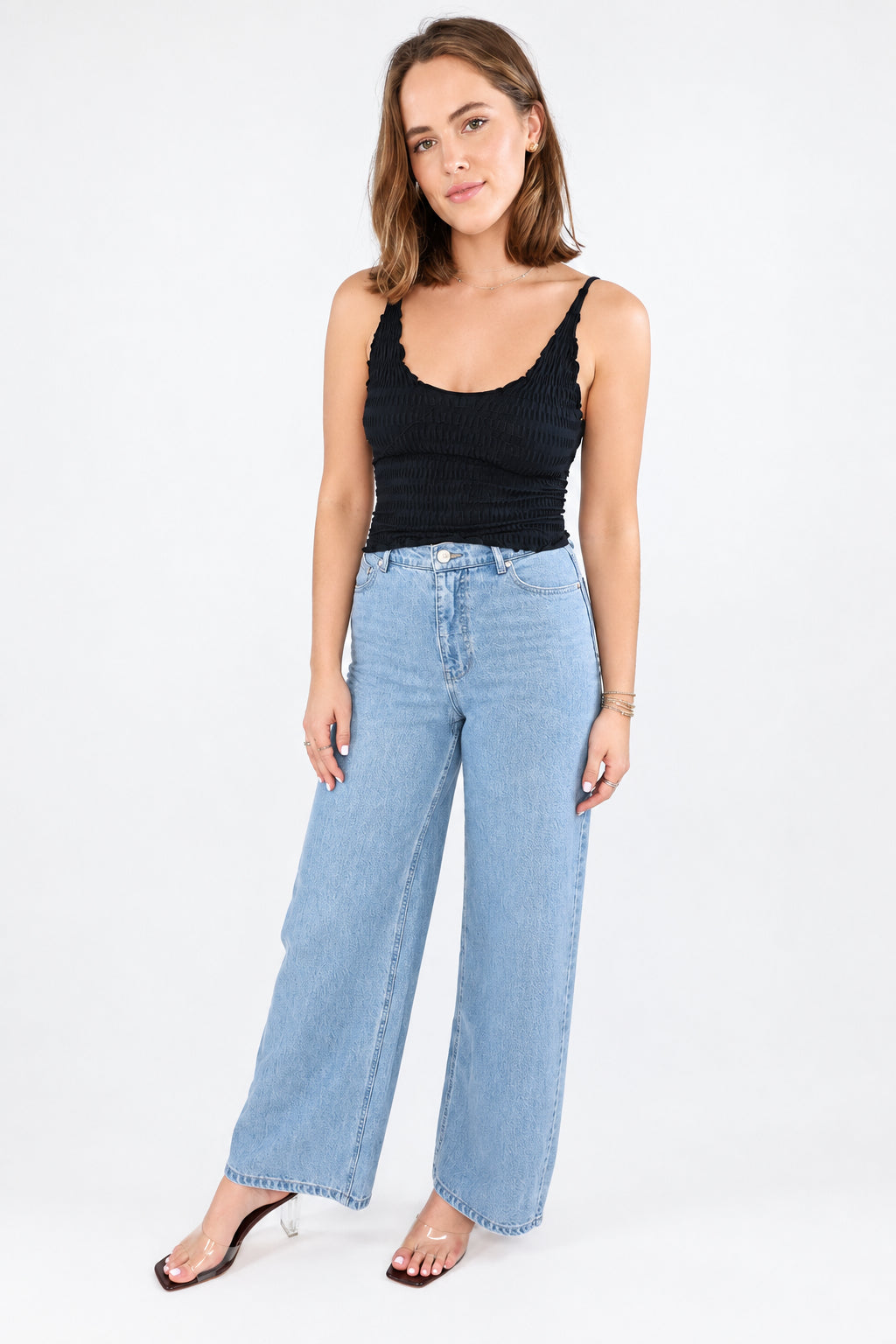 A person wearing Z Supply light-wash wide-leg denim jeans with a black top and white sneakers, standing against a plain white studio background.