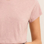 Person wearing a pink t-shirt and blue jeans with a neutral background