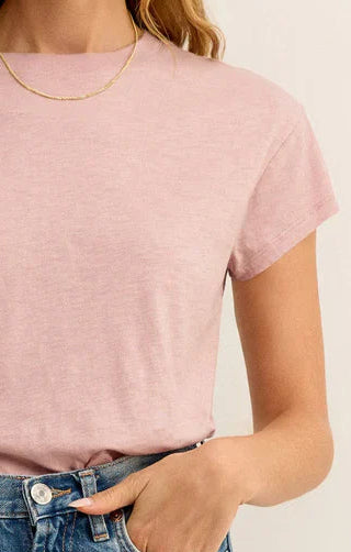 Person wearing a pink t-shirt and blue jeans with a neutral background