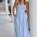 Woman wearing a blue and white striped dress standing outdoors near columns.