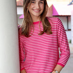 Woman wearing a pink striped shirt standing against a building.