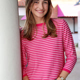 Woman wearing a pink striped shirt standing against a building.