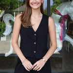 Woman wearing a black sleeveless top and shorts standing in front of a glass door with decorative elements.