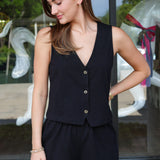 Woman wearing a black sleeveless top and shorts standing in front of a glass door.