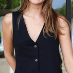 Woman wearing a black sleeveless vest with buttons outdoors