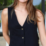 Woman wearing a black sleeveless vest with buttons outdoors