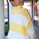 Woman wearing a yellow and white striped sweater standing outdoors.
