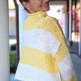 Woman wearing a yellow and white striped sweater standing outdoors.