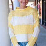 Woman wearing a yellow and white striped sweater standing outdoors.