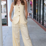 Woman wearing a light-colored suit standing on a sidewalk.