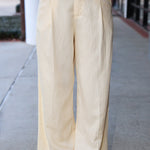 Beige wide-leg pants worn by a person on a sidewalk.