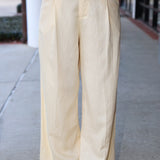 Beige wide-leg pants worn by a person on a sidewalk.