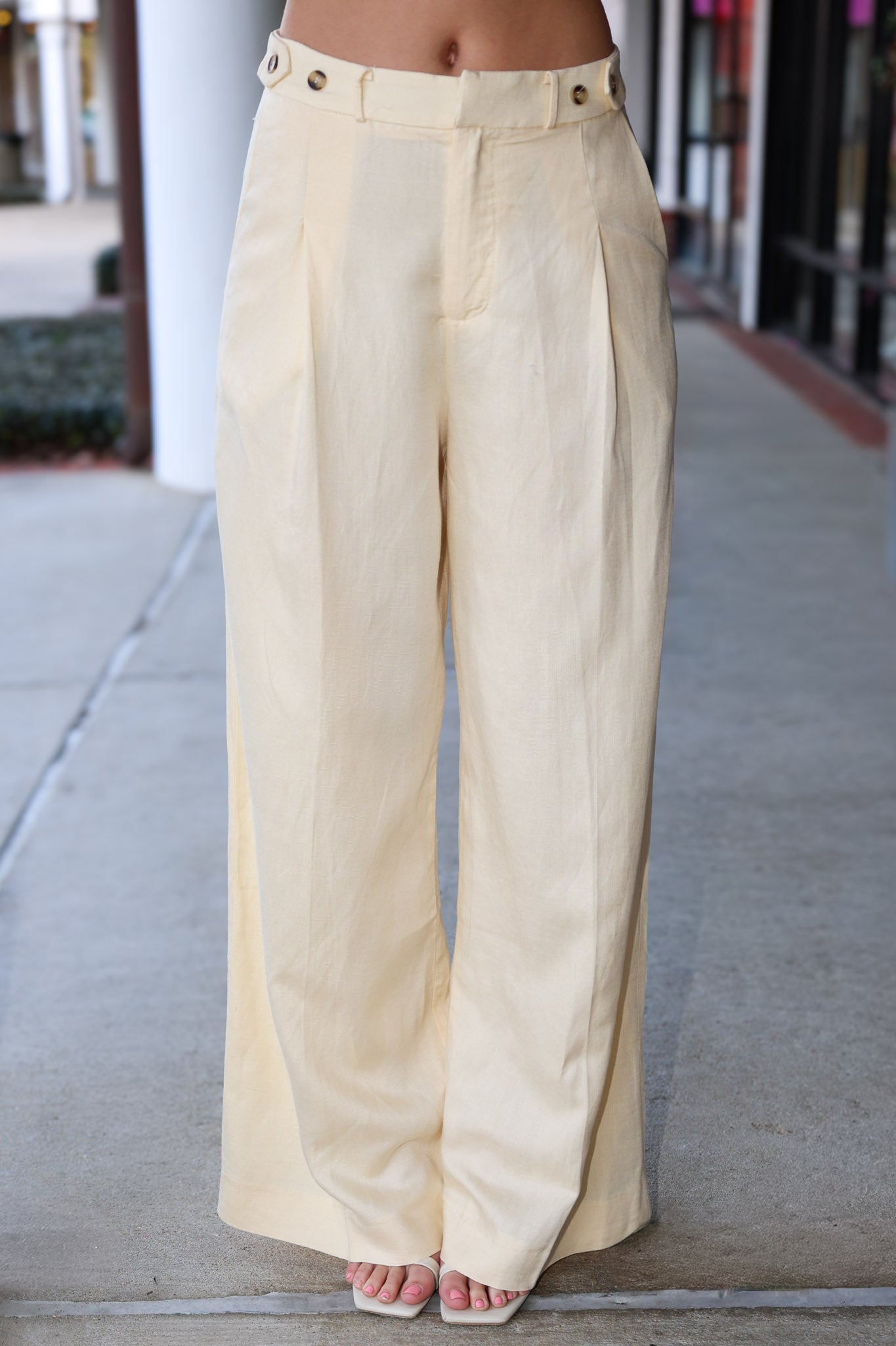 Beige wide-leg pants worn by a person on a sidewalk.