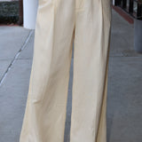 Beige wide-leg pants worn by a person on a sidewalk.