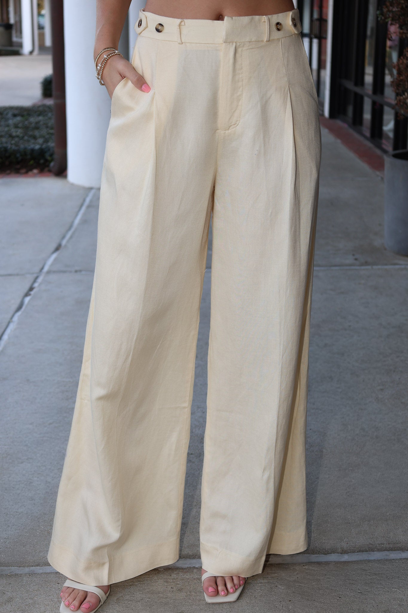 Beige wide-leg pants worn by a person on a sidewalk.