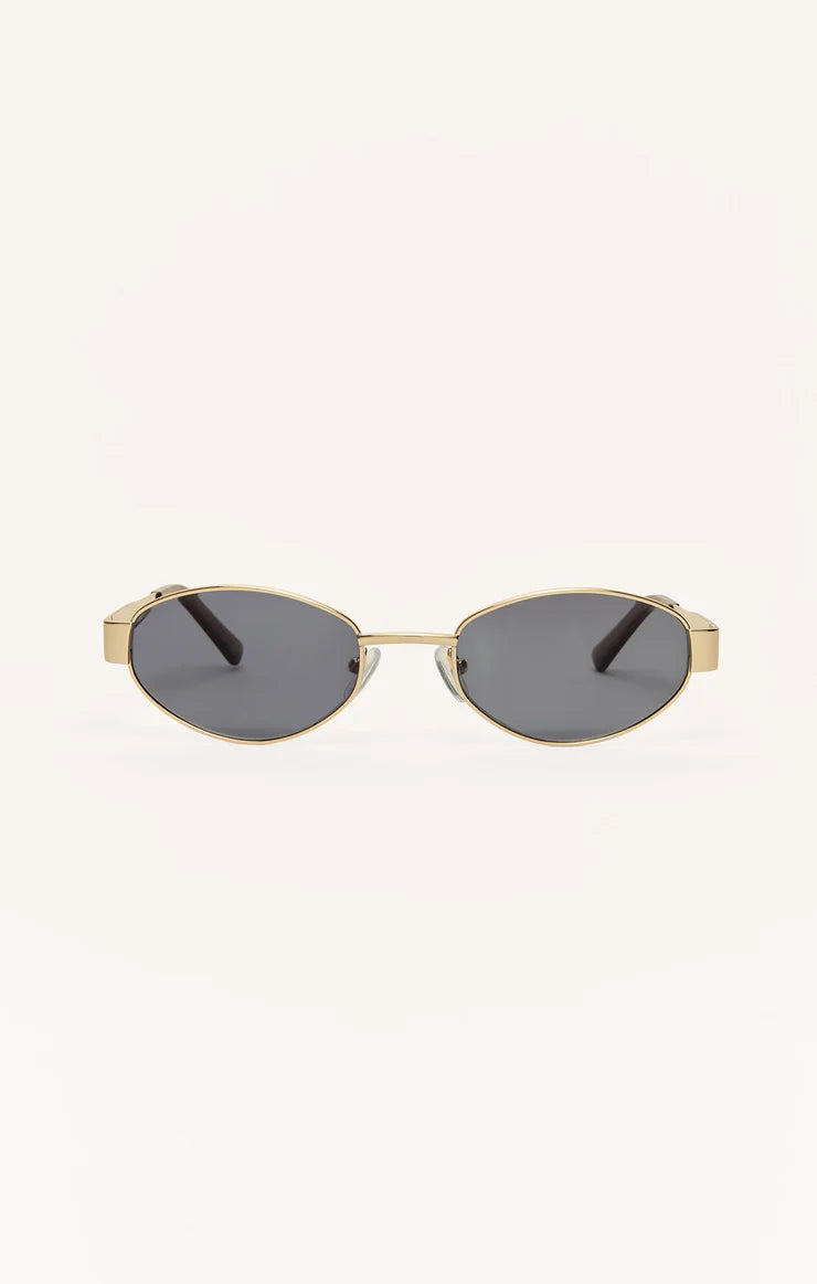 Z Supply Oval sunglasses with a gold-tone metal frame and dark gray lenses, shown from the front on a plain off-white background.