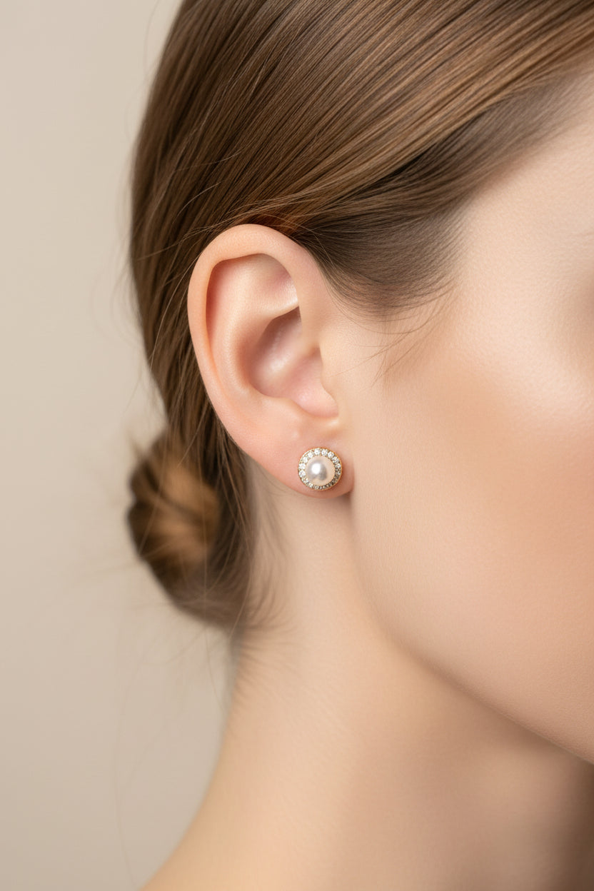 A pair of stud earrings with white pearls and gold-toned halo settings, displayed on a pink Rodéo Boutique card against a light gray background.