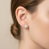 A pair of stud earrings with white pearls and gold-toned halo settings, displayed on a pink Rodéo Boutique card against a light gray background.