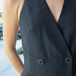 Black sleeveless blazer with white collar worn by a person outdoors.