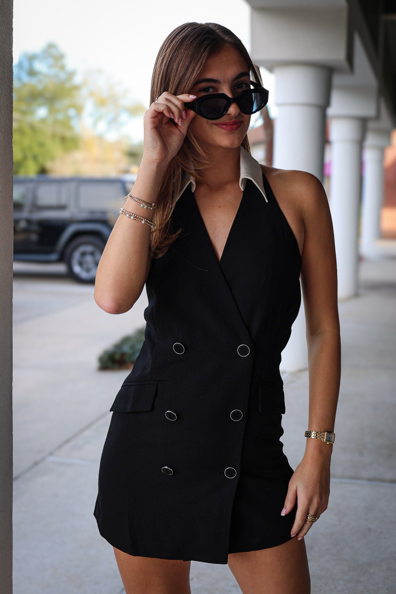 Woman wearing a black blazer dress with sunglasses outdoors.
