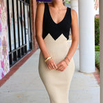 Woman wearing a black and beige dress standing outdoors.