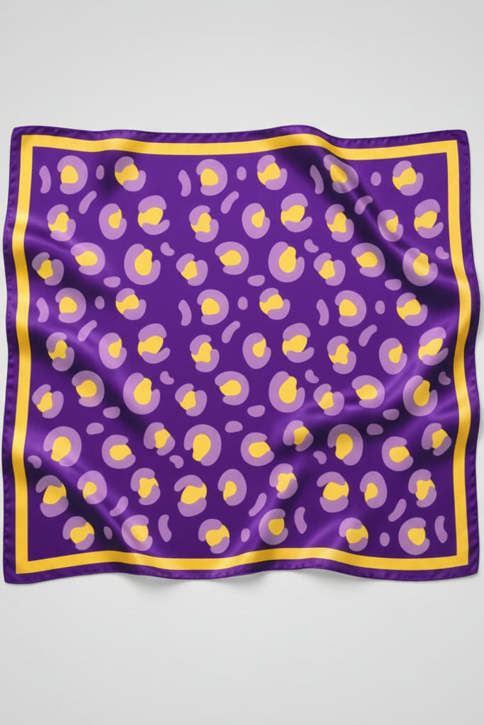 A square purple silk scarf with a yellow and light purple abstract pattern and a yellow border, displayed flat against a white background.