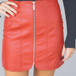 Red leather skirt with a zipper on a plain background