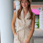 A woman wearing a beige sleeveless belted romper and a matching cowboy hat, standing in a covered walkway near Rodéo Boutique.