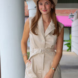 A woman wearing a beige sleeveless belted romper and a matching cowboy hat, standing in a covered walkway near Rodéo Boutique.
