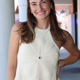 Woman wearing a white sleeveless top with a textured pattern, standing outdoors.