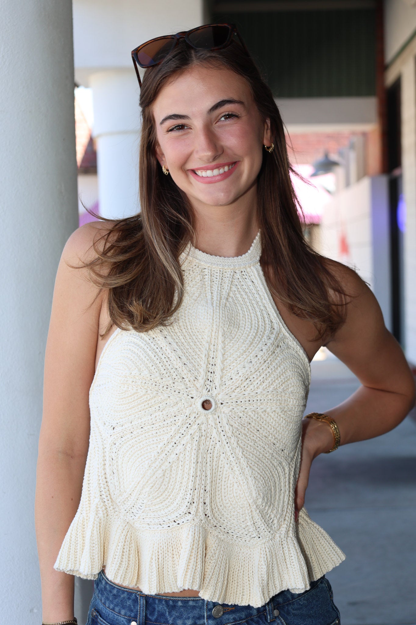 Woman wearing a white sleeveless top with a textured pattern, standing outdoors.