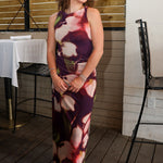 Rylen Midi Dress by Steve Madden is sleeveless, floor-length halter dress with a dark purple base and a large floral print in pink, red, and white. 