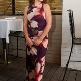 Rylen Midi Dress by Steve Madden is sleeveless, floor-length halter dress with a dark purple base and a large floral print in pink, red, and white. 