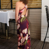 Rylen Midi Dress by Steve Madden is sleeveless, floor-length halter dress with a dark purple base and a large floral print in pink, red, and white. 