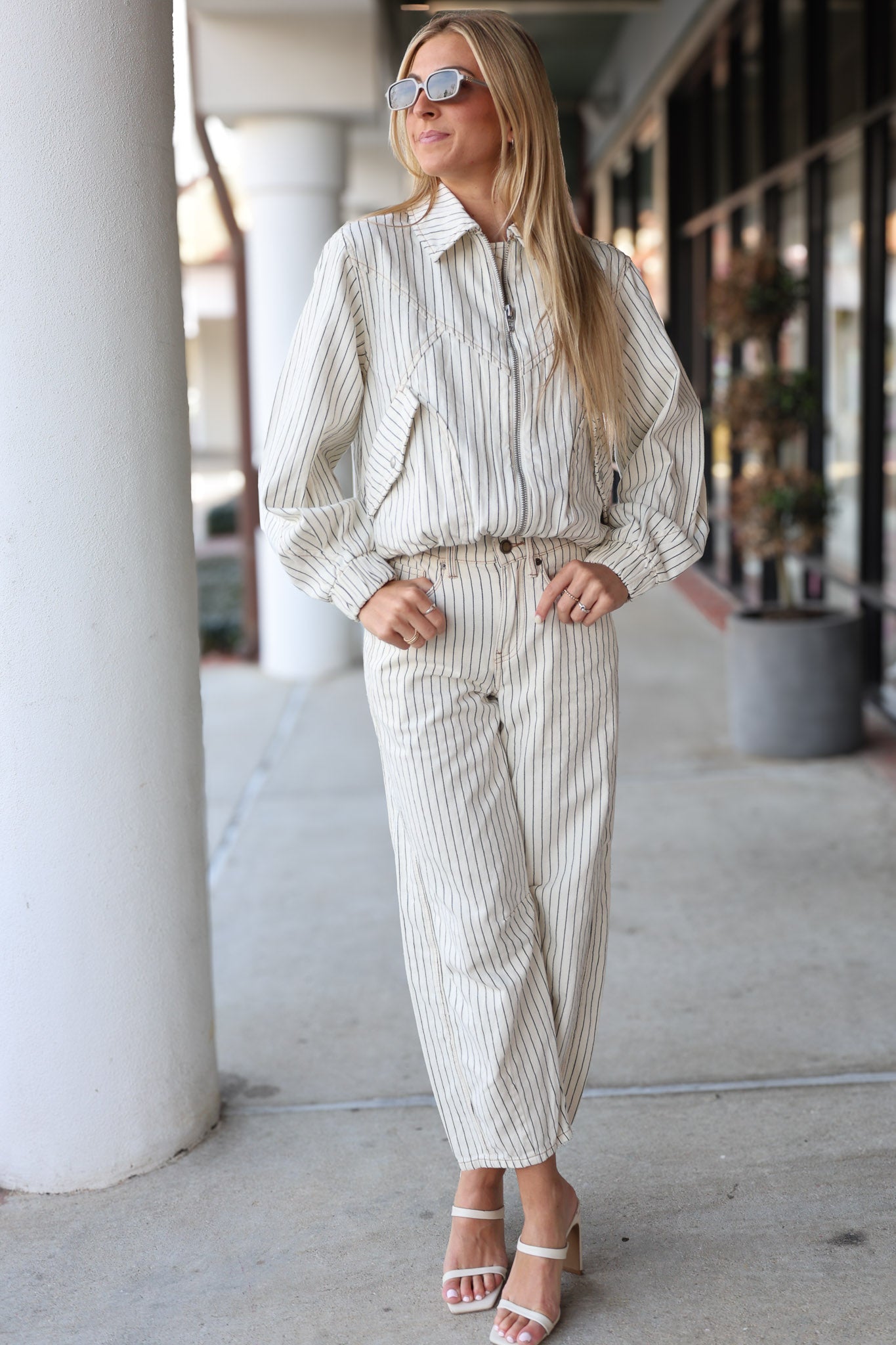 Woman wearing a striped pants 
outfit with sunglasses in an urban setting