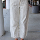 Person wearing white and gray striped pants on a sidewalk.