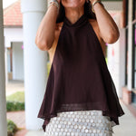 A woman laughing at Rodéo Boutique, wearing a dark brown sheer halter top and a white sequined mini skirt.