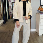 Woman in a stylish outfit standing in an interior setting with decor elements.