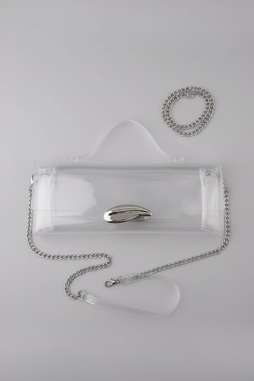 A clear vinyl handbag with a silver chain strap and a metallic silver clasp, displayed on a white surface against a black background.