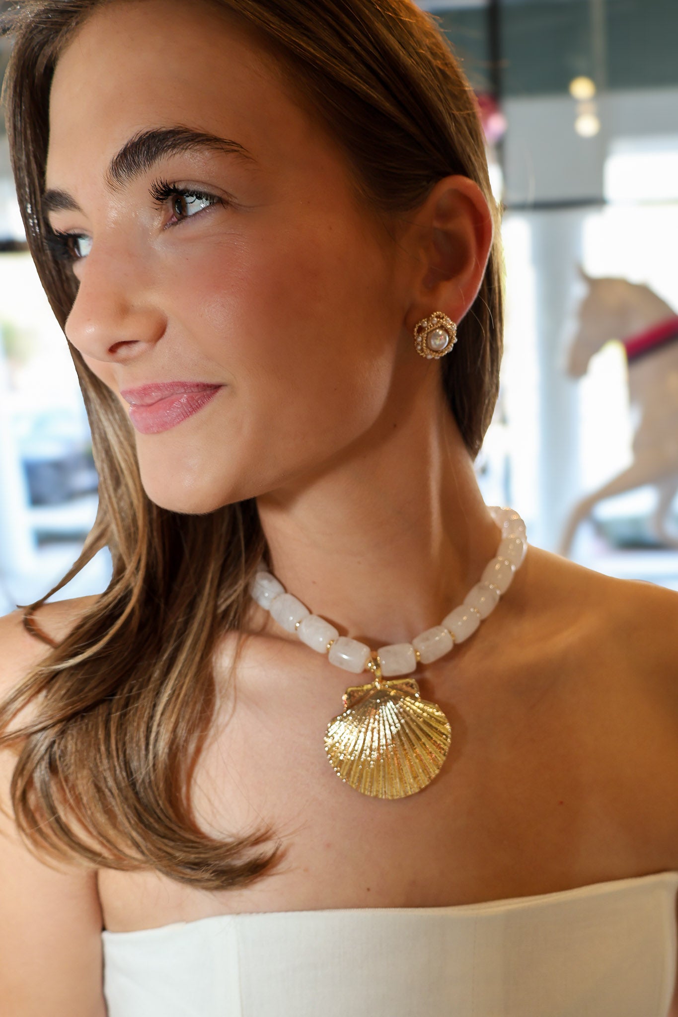Woman wearing a necklace and earrings with a blurred background