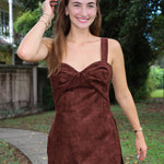 A woman wearing the Soho Romper by Amanda Uprichard. a brown faux suede mini dress with a sweetheart neckline.