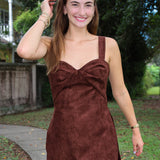 A woman wearing the Soho Romper by Amanda Uprichard. a brown faux suede mini dress with a sweetheart neckline.