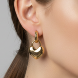 Gold heart-shaped padlock style earring worn by a person with a neutral background