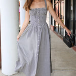 Woman wearing a black and white checkered dress standing outdoors.