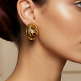 A pair of gold hoop earrings with three brown tiger's eye stones each, displayed on a pink Rodéo Boutique card.