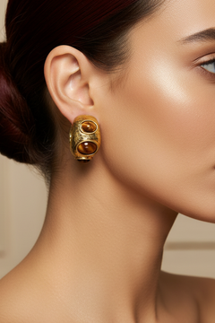 A pair of gold hoop earrings with three brown tiger's eye stones each, displayed on a pink Rodéo Boutique card.