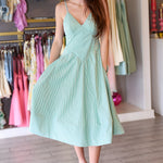 Woman wearing a light green seersucker dress in a clothing store.