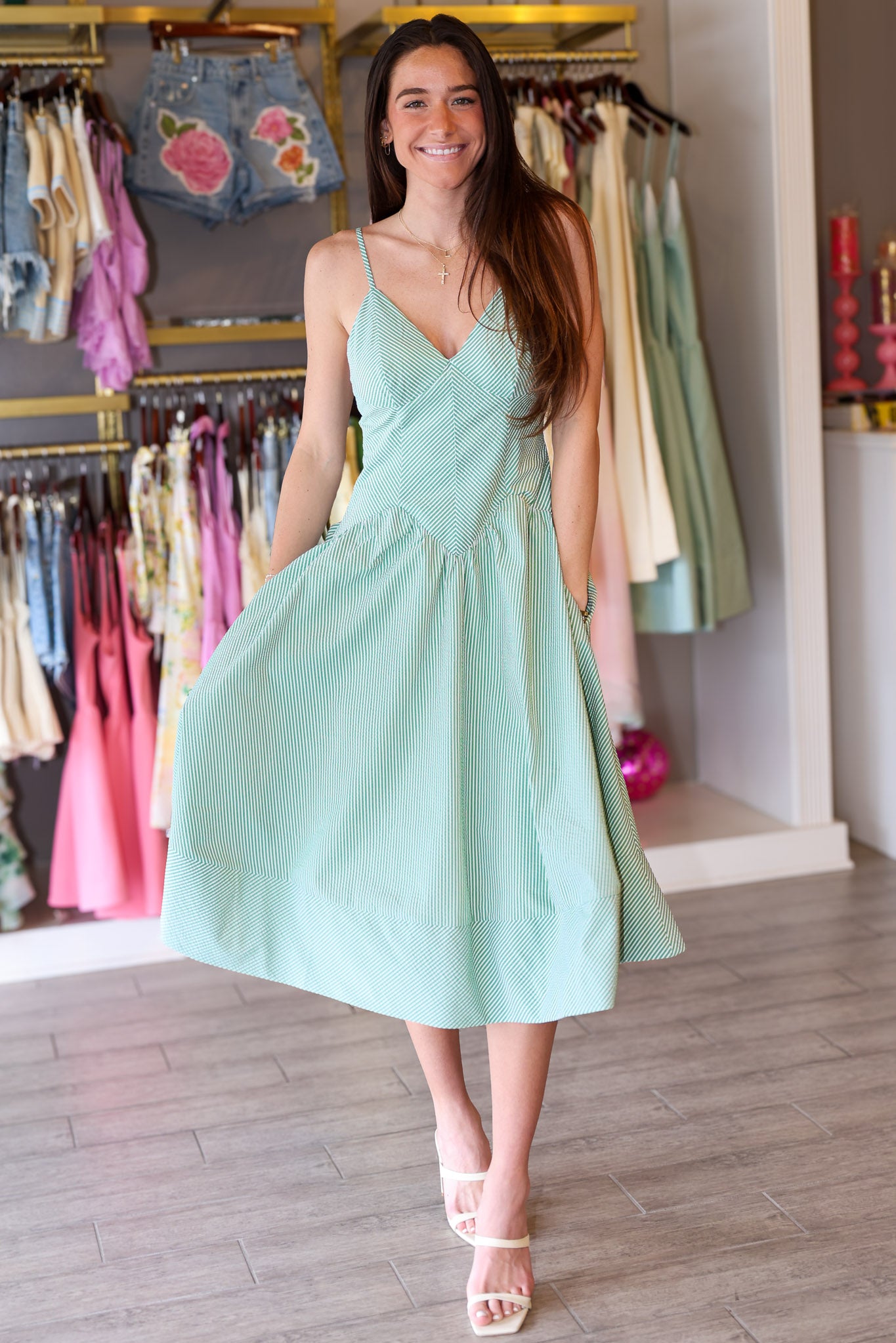 Woman wearing a light green seersucker dress in a clothing store.