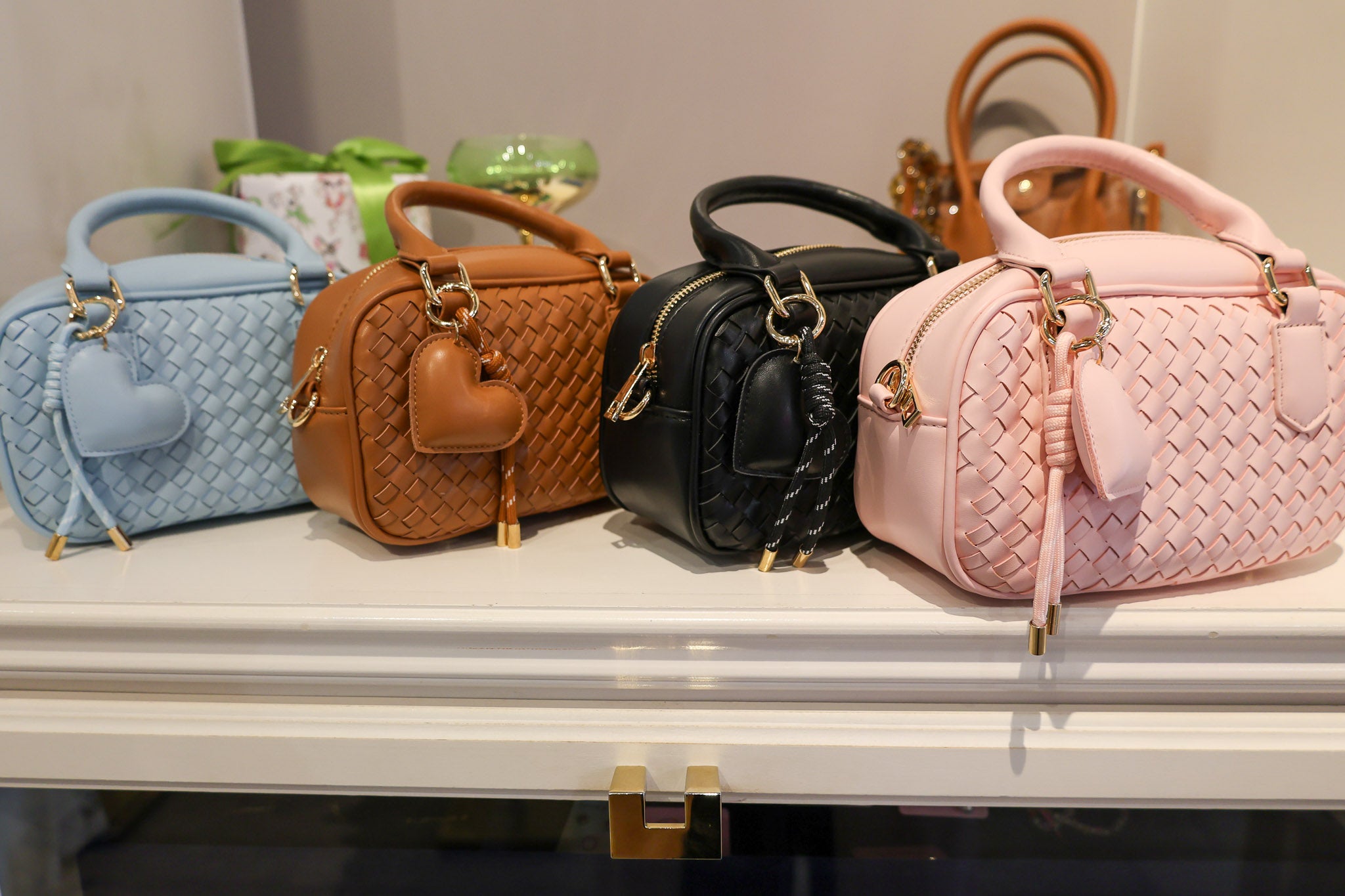 Four handbags in different colors on a display table.